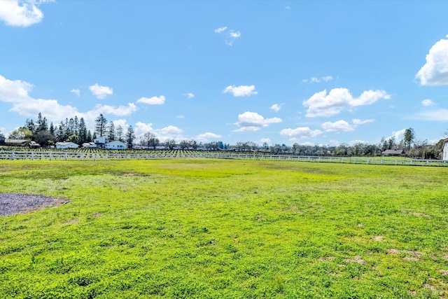 view of yard with fence and a rural view