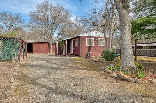 exterior space with an outbuilding, driveway, a storage unit, and fence