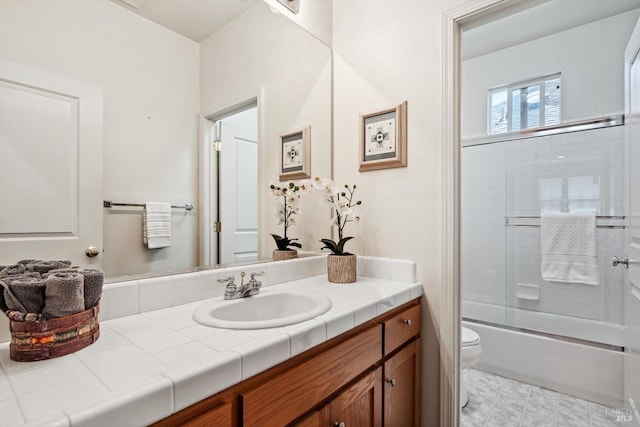 bathroom with vanity, toilet, and bath / shower combo with glass door