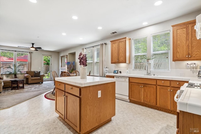 kitchen featuring tile countertops, light floors, open floor plan, and dishwasher