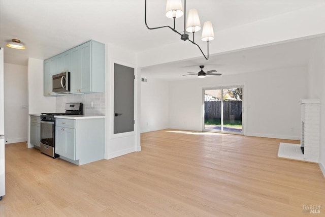 kitchen featuring light wood-type flooring, tasteful backsplash, appliances with stainless steel finishes, and open floor plan