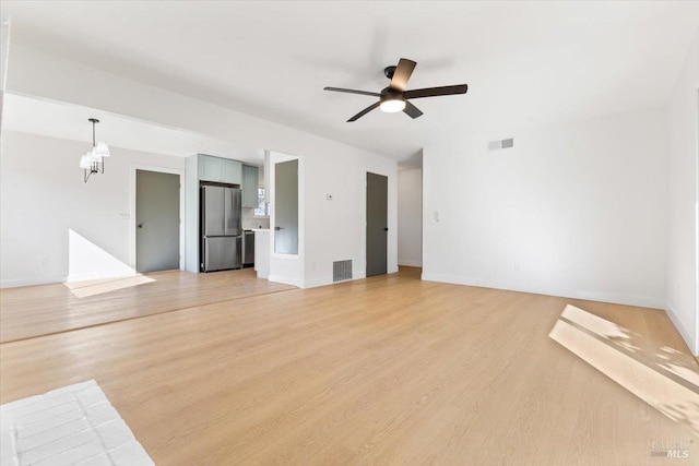 unfurnished living room with light wood-style flooring, visible vents, baseboards, and ceiling fan with notable chandelier