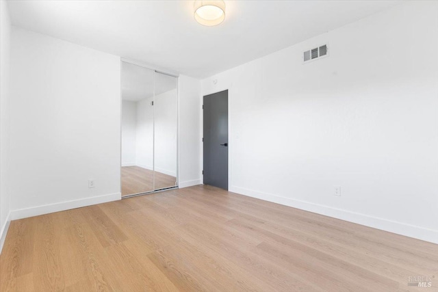 spare room with visible vents, baseboards, and wood finished floors