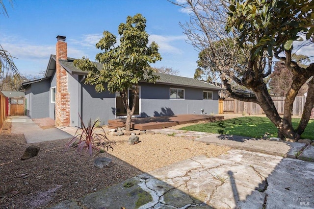 ranch-style house featuring a chimney, fence, a patio area, a front lawn, and stucco siding