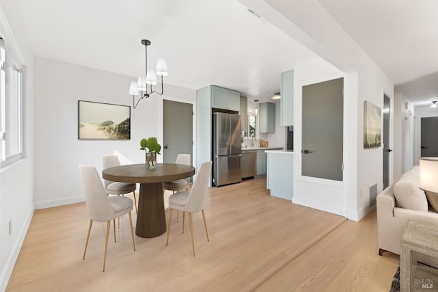 dining space featuring baseboards, visible vents, a notable chandelier, and light wood finished floors