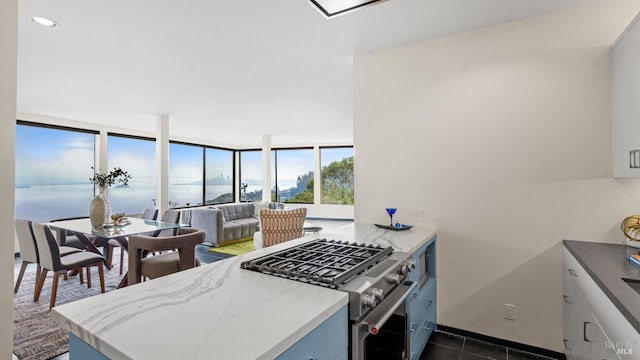 kitchen with stainless steel gas range oven, light stone counters, recessed lighting, a peninsula, and open floor plan