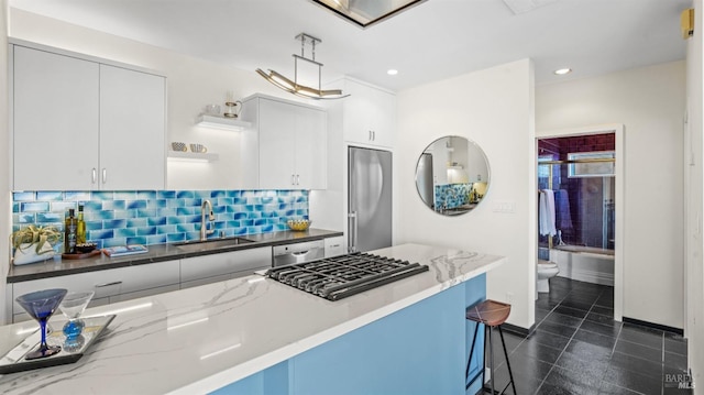 kitchen with stainless steel appliances, a sink, white cabinetry, decorative backsplash, and open shelves