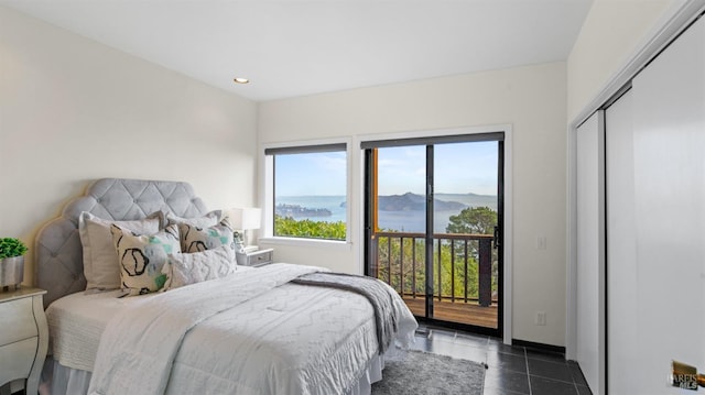 bedroom with dark tile patterned floors, access to outside, and a mountain view