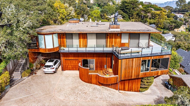 rear view of property with a garage, driveway, and stairway