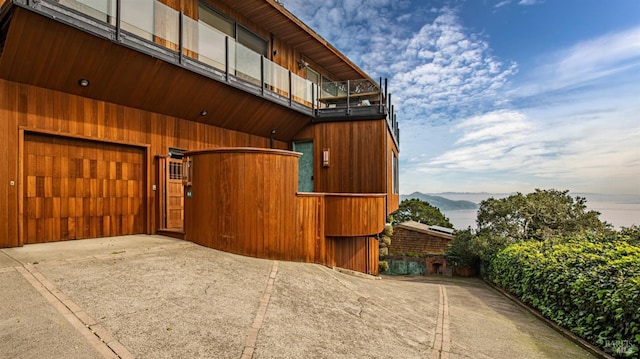 exterior space featuring an attached garage, a balcony, driveway, and a mountain view