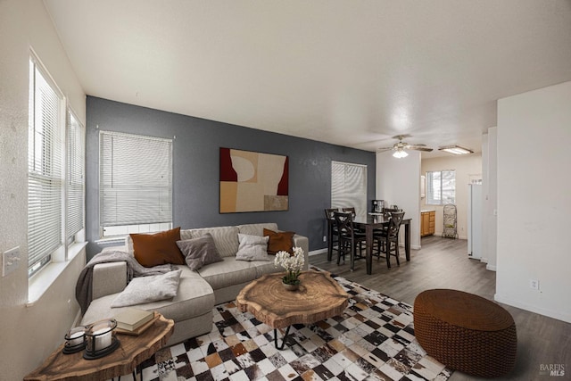 living room with ceiling fan, baseboards, and wood finished floors