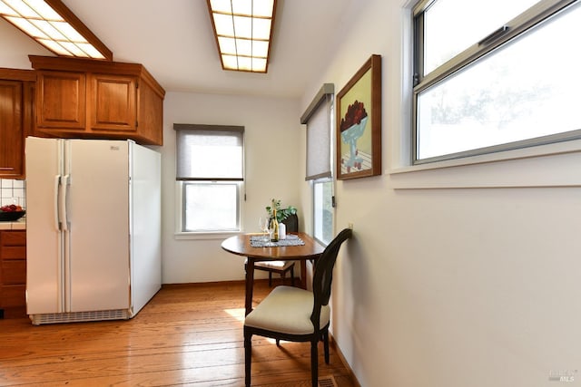 kitchen featuring light wood-style flooring, brown cabinetry, and freestanding refrigerator