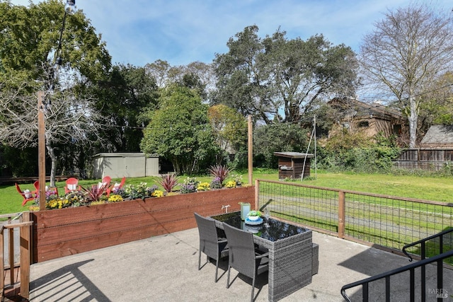 view of patio / terrace with a shed, fence, an outbuilding, and outdoor dining space