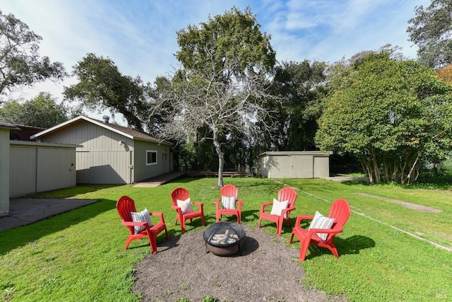 view of yard with an outdoor fire pit, an outbuilding, and a storage unit