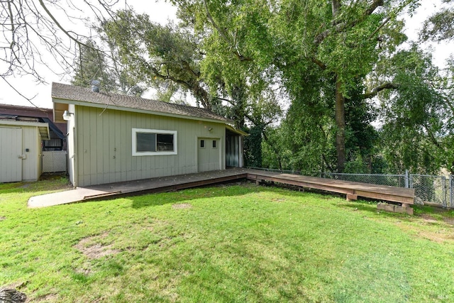 back of house featuring an outbuilding, a yard, a deck, and fence