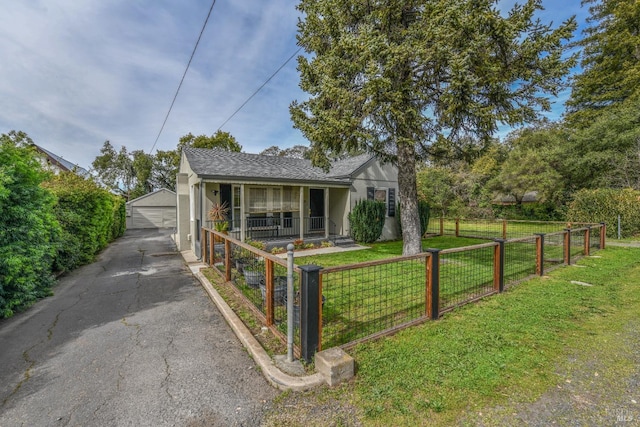 view of front of house featuring a fenced front yard, stucco siding, covered porch, an outdoor structure, and a front lawn