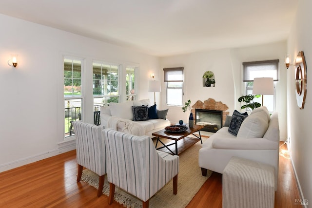 living area with a fireplace, wood finished floors, and baseboards