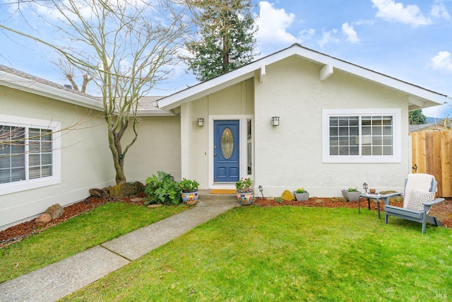 view of front of home with a front yard, fence, and stucco siding