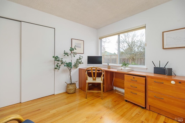 office with light wood-style flooring and a textured ceiling