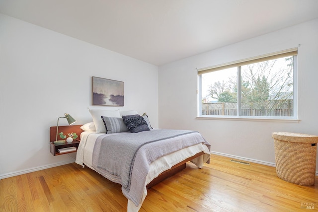 bedroom featuring light wood finished floors, baseboards, and visible vents