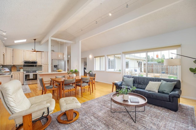 living room featuring lofted ceiling with beams, a textured ceiling, light wood-type flooring, and baseboards