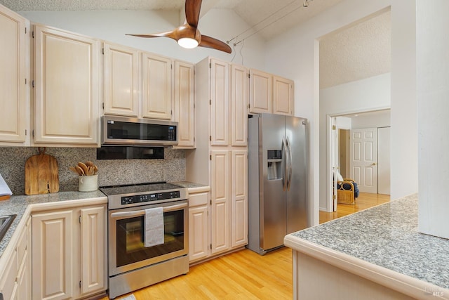 kitchen featuring light wood finished floors, tasteful backsplash, tile countertops, ceiling fan, and stainless steel appliances