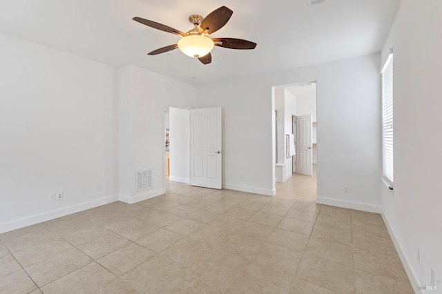 empty room with a wealth of natural light, light tile patterned flooring, visible vents, and baseboards