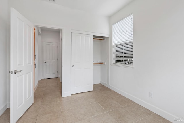 unfurnished bedroom with baseboards, a closet, and light tile patterned flooring