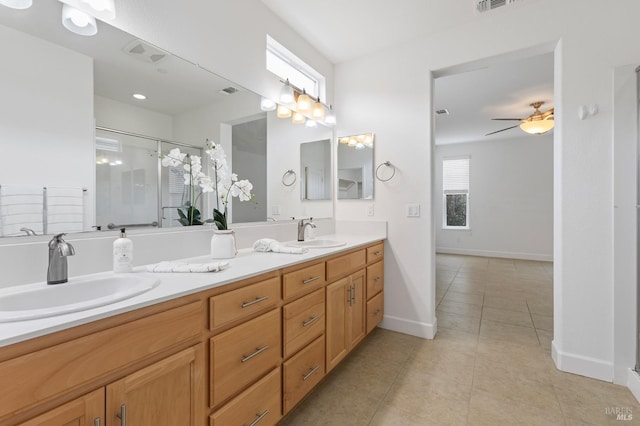 bathroom with double vanity, a sink, a shower with door, and tile patterned floors