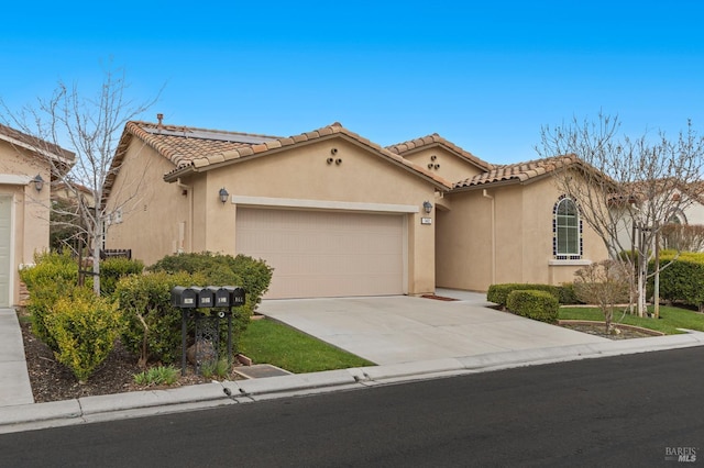 mediterranean / spanish home with driveway, an attached garage, a tile roof, and stucco siding