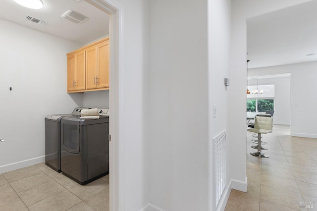 laundry room with washing machine and clothes dryer, light tile patterned floors, visible vents, cabinet space, and baseboards