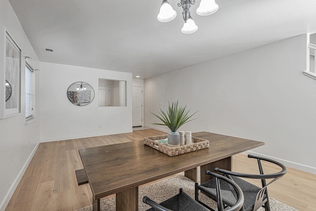 dining room with a chandelier, visible vents, light wood-type flooring, and baseboards