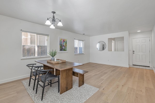 dining space featuring a notable chandelier, baseboards, and light wood-type flooring