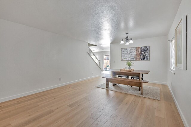 dining space featuring a wealth of natural light, a notable chandelier, light wood-style floors, and stairway