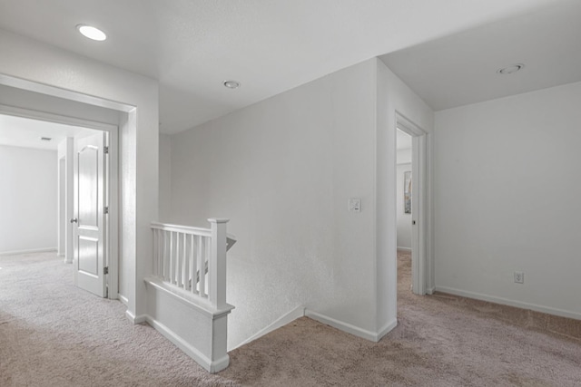 hallway with an upstairs landing, carpet, and baseboards