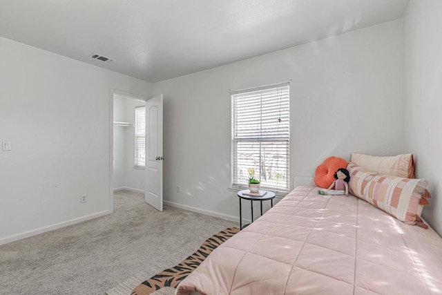 carpeted bedroom featuring a spacious closet, visible vents, and baseboards