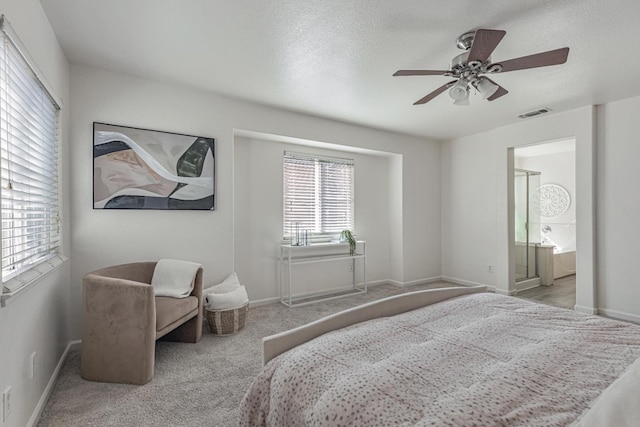 carpeted bedroom featuring visible vents, baseboards, ensuite bathroom, a textured ceiling, and a ceiling fan