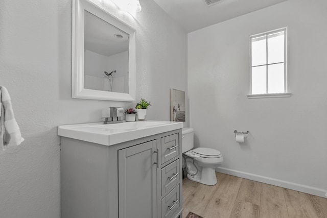 full bathroom featuring vanity, wood finished floors, baseboards, a shower, and toilet