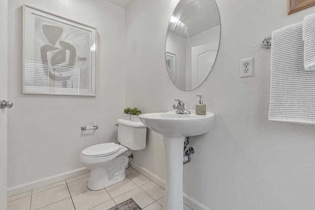 bathroom with tile patterned floors, toilet, baseboards, and a sink