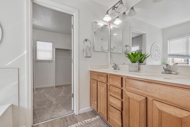 bathroom with double vanity, a healthy amount of sunlight, a textured ceiling, and a sink