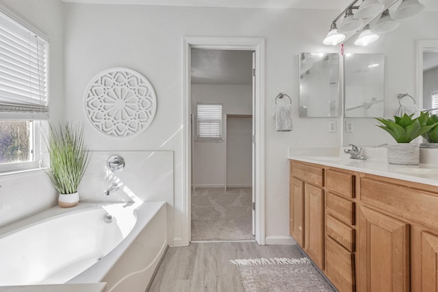 full bathroom with wood finished floors, a textured ceiling, a bath, and vanity