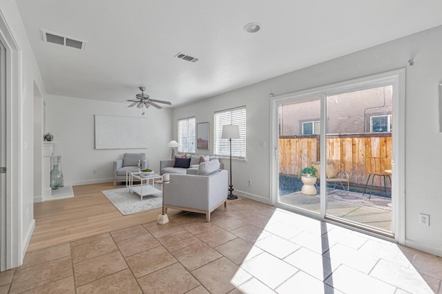 living room with light tile patterned flooring, a ceiling fan, and visible vents