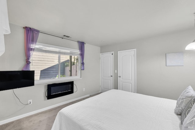 carpeted bedroom featuring visible vents, baseboards, and a glass covered fireplace