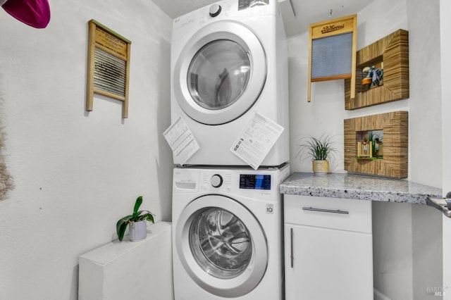 washroom with cabinet space and stacked washing maching and dryer