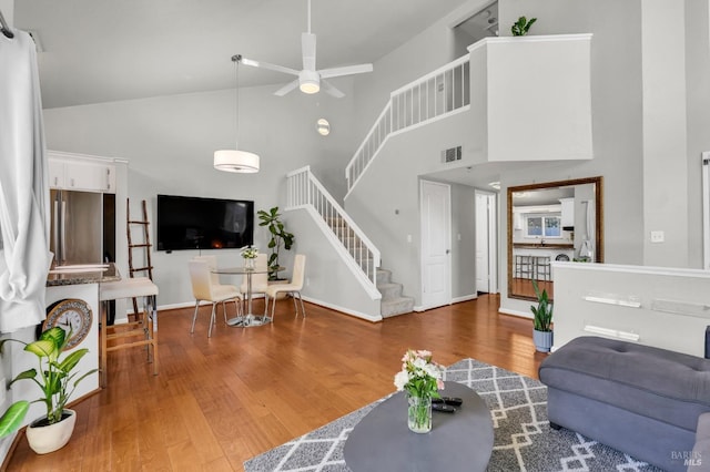 living area featuring visible vents, high vaulted ceiling, stairs, and wood finished floors