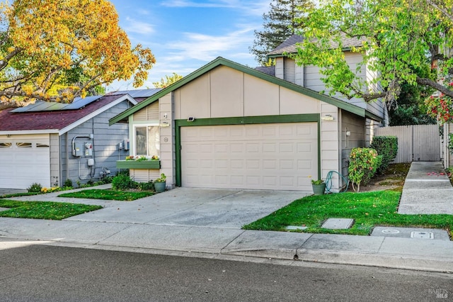 view of front of house with fence, solar panels, an attached garage, a shingled roof, and concrete driveway