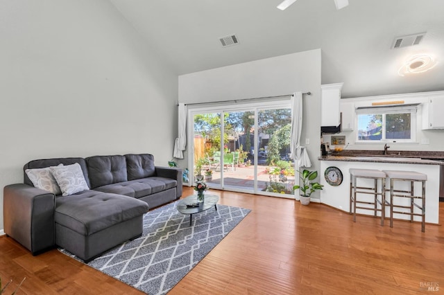 living area featuring visible vents, high vaulted ceiling, and wood finished floors