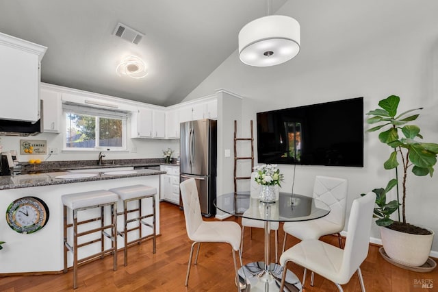 kitchen featuring light wood-type flooring, visible vents, freestanding refrigerator, a peninsula, and white cabinets