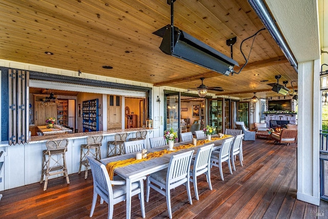 dining space with a fireplace, a ceiling fan, wood ceiling, beamed ceiling, and hardwood / wood-style flooring