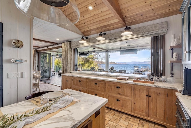 kitchen featuring brick floor, brown cabinetry, wood ceiling, light stone countertops, and beamed ceiling